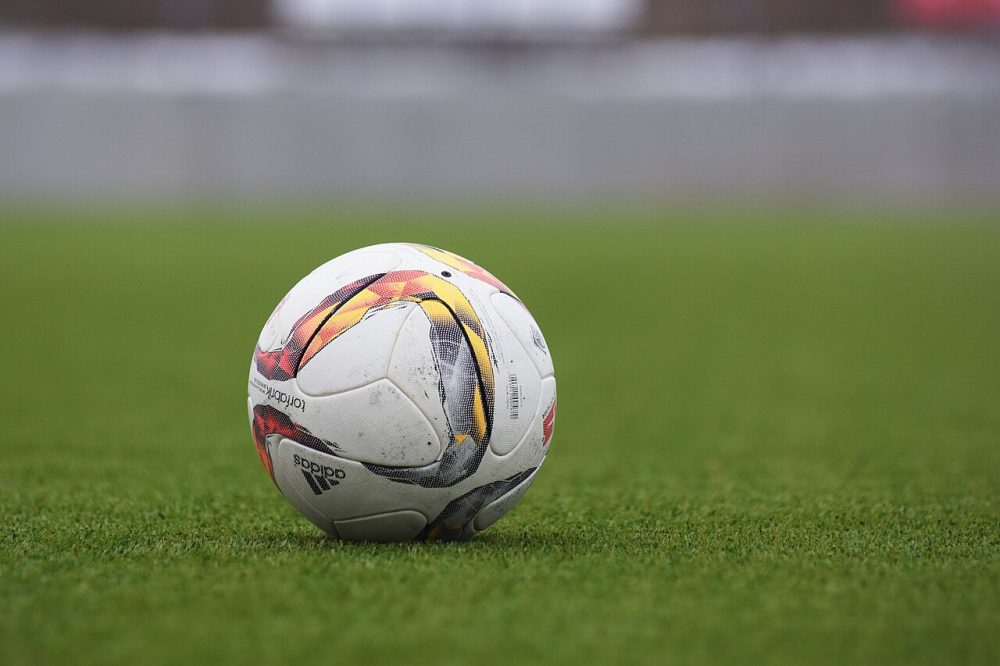 Adidas soccer ball on a grass pitch (Unsplash)